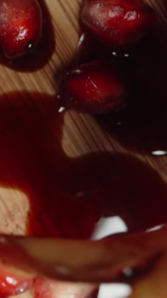 バーティカルビデオ ポメグラネートの種子と赤いジュースがテーブルにこぼれました トップダウンビュー ドリースライダー極端なクローズアップ — ストック動画