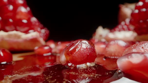 黒い背景に 上から滴るジュースが付いている赤いポメグラネートの種子は ゆっくりと種の上にカスケードします クローズアップ — ストック動画