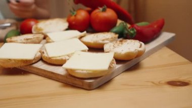 Akşamları sıcak bir atmosferde bir kadın hamburgerleri hazırlar. Peynirin üzerine sos serpiyor. Çöreğin üzerine yerleştirilmiş. Yavaş Çekim, Hareketli Yakın Çekim.