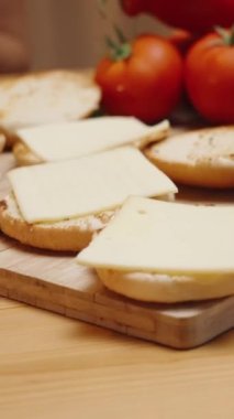 Dikey video. Akşamları sıcak bir atmosferde bir kadın hamburgerleri hazırlar. Peynirin üzerine sos serpiyor. Çöreğin üzerine yerleştirilmiş. Yavaş Çekim, Hareketli Yakın Çekim.