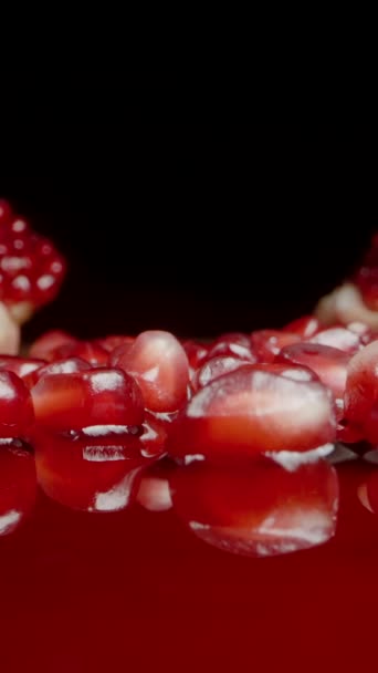 バーティカルビデオ ザクロの果実からこぼされた赤い種子は ジュースに休んでいます ドリースライダー極端なクローズアップ — ストック動画