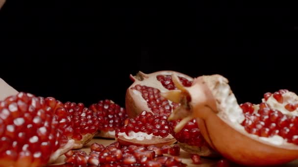 ポメラニアの季節とテーブルの上には 赤い種子が付いている多数の開いた果物があります 若い女性は1つの部分を噛みます — ストック動画