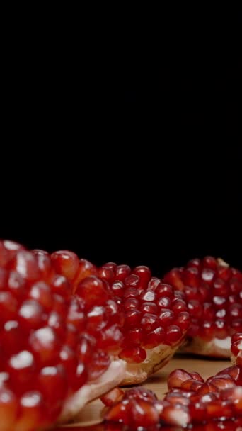 バーティカルビデオ ポメラニアの季節とテーブルの上には 赤い種子が付いている多数の開いた果物があります 若い女性は1つの部分を噛みます — ストック動画