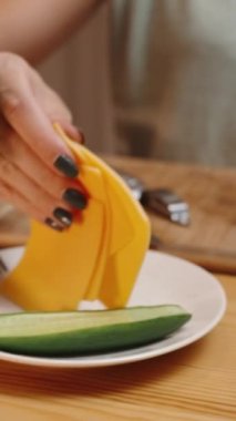 Dikey video. Homey Setting 'deki hamburgerlerin hazırlanması, üstüne peynir dilimleri konur. Malzemeler masada ve hamburgerler neredeyse hazır. Ağır çekimde.