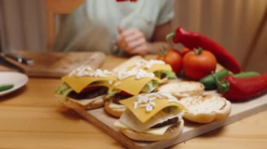 Ev yapımı burgerlerin üzerine hardal döken bir kadın. Evde Sıcak Bir Akşam.