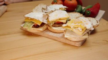 Ev Yapımı Yemeklerin Hazırlanması. Neredeyse hazır hamburgerler, yakınlarda sebzeler. Arka planda bir kadın var. Kamera hareketi dairesel hareketle, ağır çekimde. Sinematik.