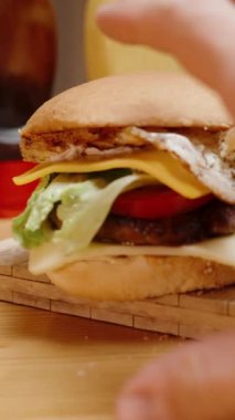 Dikey video. Ev Yapımı ve Ev Yapımı Burgerler. Bir erkek eli onlara uzanıyor ve bir tanesini alıyor..