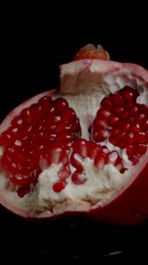 Dikey video. Kırmızı tohumlu yarım bir Split Nar, izole edilmiş, döngülü video. Arkaplan kaldırma için uygun.