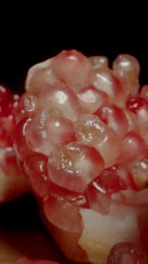 Dikey video. İki çeşit nar, kırmızı ve beyaz tohumlar, bölünüp masaya saçılırlar. Dolly kaydırıcı aşırı yakın çekim.