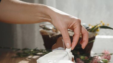 Bir kadın ev yapımı paskalya pastalarını küçük çikolatalı yumurtalarla süslüyor..