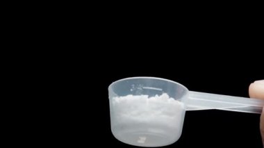 Yavaş çekimde, bir ölçü kaşığından çıkan beyaz toz doğrudan size doğru uçar ve tüm kareyi doldurur. Spor desteği ya da ilaç konsepti.