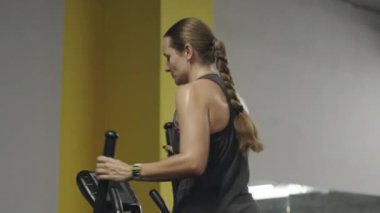 Eliptik Eğitimli Genç Kadın, Terli ve Yorgun, Öne Eğiliyor.