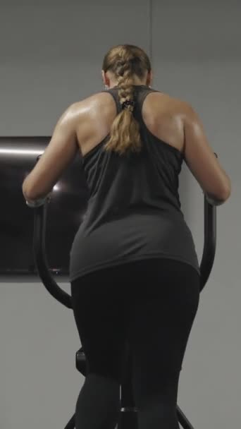 Vertical Video Woman Long Hair Tied Braid Exercising Elliptical Trainer — Stock Video