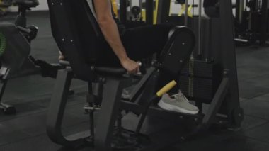 Spor Salonunda Siyah Pantolon Giyen Kadın Spor Makinesinde Bacak Kaçırma Yapıyor. Arka Görünüm!