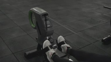 Genç bir kadın kürek makinesinde kardiyo çalışması yapıyor..