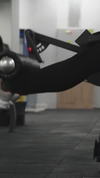 バーティカルビデオ 座席の機械で脚延長運動をしている若い女性 — ストック動画
