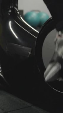 Dikey video. Beyaz spor ayakkabılı kadın bacakları Sabit bir bisiklette pedal çeviriyor!