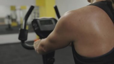 Sabit bir bisiklette kardiyo çalışması. Ter içinde ışıl ışıl, Kadın Sırtı. Yağ Yakma Egzersizleri.