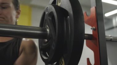 Halterin üzerinde ağırlık plakalarını koruyan genç bir kadın özel klemp kullanıyor. Yakın plan!