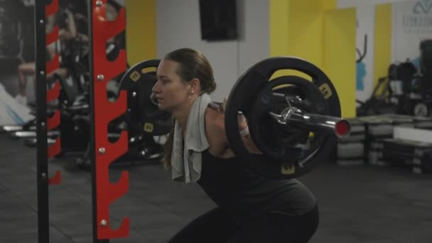 그녀의 어깨에 무거운 바벨과 스쿼트를 운동선수 지원을 그녀의 접시를 — 비디오