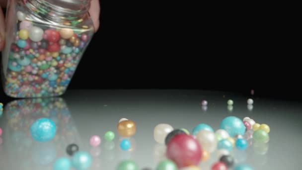 在我放下罐子的时候 洒糖和装饰糖的彩色糖球撒在桌子上 — 图库视频影像