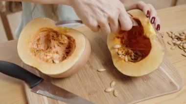 Bir kaşıkla, kadın küçük bir balkabağının tohumlarını kepçeleyip sonra dilimleyip pişirmek niyetinde. Yavaş çekim.