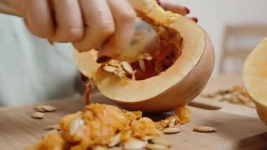 Yarım Balkabağı 'nın Yakın Çekimi Bir Kadın Kaşıkla Tohumları Çekiyor. Yavaş çekim.