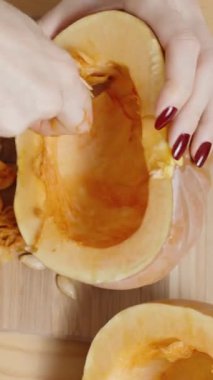 Dikey video. Top View, Kamera Bir Kadın Balkabağı Tohumlarını Temizlerken Yaklaşıyor. Tahta Masa 'da.