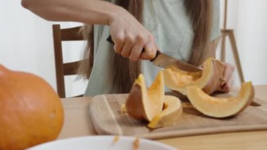 Uzun Saçlı Kadın Tahta Tahtada Küçük Balkabağını Dilimliyor. Ağır çekim. Yakın plan..