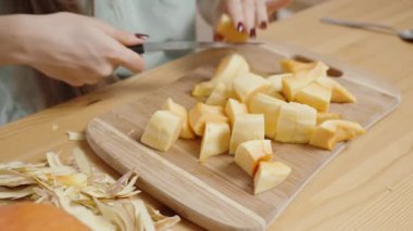 Tahta bir kesme tahtasının üzerinde, bir kadın bir tarif için balkabağını keser..