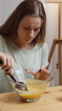 Dikey video. Balkabağı kurabiyeleri için malzemeler. Genç bir kadın ev ortamında hazırlanıyor, hamuru karıştırıyor..