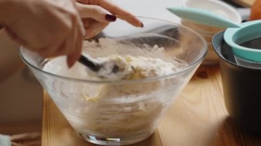 Kadın spatulayla hamuru kasede karıştırıyor..