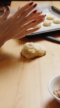 Dikey video. Kadın küçük hamur parçalarını koparıp toplara sarar ve onları pişirme tepsisine aktarır. Balkabağı ve fındıklı ev yapımı kurabiye tarifi..