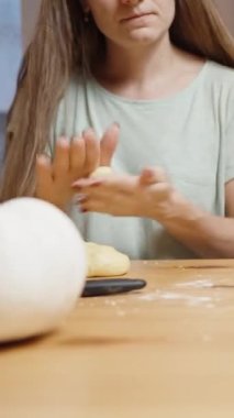 Dikey video. Sade bir atmosferde, genç bir kadın hamur toplarını yuvarlar ve balkabağı kurabiyesine dönüşür..