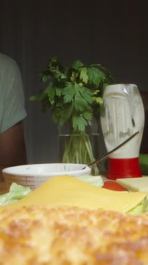 Dikey video. Kadın ev yapımı hamburgerleri hazırlıyor tavuk köftelerini peynirin üzerine koyuyor. Dolly kaydırıcı aşırı yakın çekim.