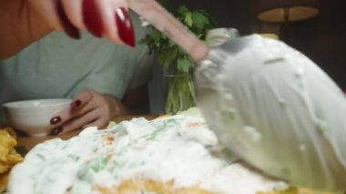 Ev yapımı hamburgerler hazırlıyor, köftelere sos sürüyor. Dolly kaydırıcı aşırı yakın çekim.