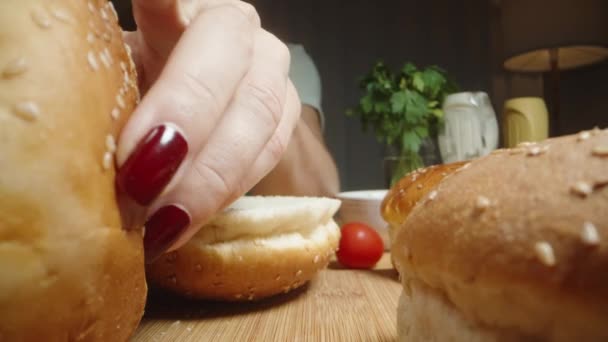 Ung Kvinna Skär Hamburgerbullar Och Inspekterar Något Dem Kanske Bortskämda — Stockvideo