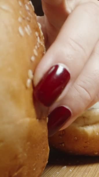 垂直录像 一个年轻的女人把汉堡包切成薄片 然后检查里面的东西 也许他们被宠坏了回家吃晚饭 多利滑翔机极端特写 — 图库视频影像