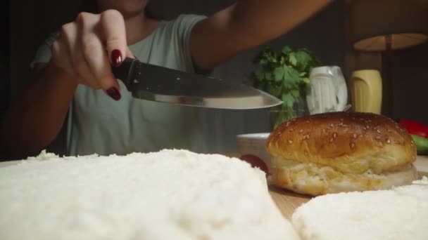 在准备自制汉堡包时 一个女人把面包切成两半 配料在桌子上 多利滑翔机极端特写 — 图库视频影像