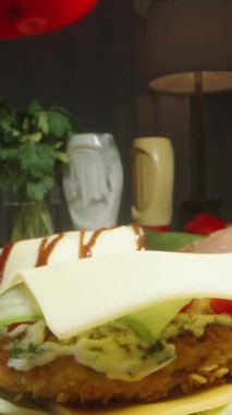 Dikey video. Genç bir kadın tarafından hazırlanmış ev yapımı hamburgerler, üzerine sos döküyor. Odada alacakaranlık, loş ışık. Dolly kaydırıcı aşırı yakın çekim.