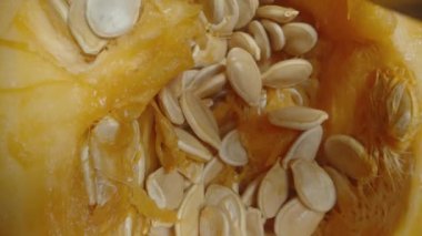 Hokkaido balkabağının tohumlarını kaşıkla temizlerken tohumları ahşap bir masaya yerleştiriyorum. Üst görünüm, makro kaydırıcı.