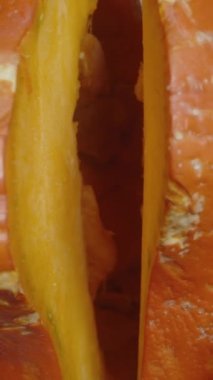 Dikey video. Hokkaido balkabağı ikiye ayrılırken en üstteki görüntü makro çekimleri içeriden yakalıyor. Doli..