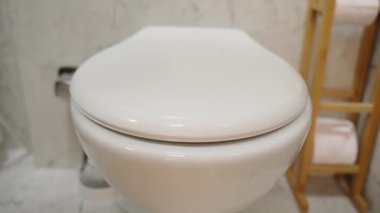 Beyaz bir tuvaletin yakın plan görüntüsü, erkek eli Lid 'i kaldırırken....