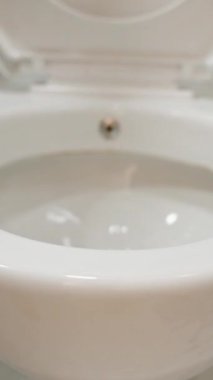 Dikey video. Beyaz Parlak Tuvaletin Yakın Çekimi. Eylemdeki Yumuşak Kapatma Mekanizması.
