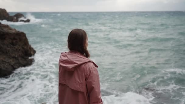 여자가 가장자리에 바위에 바위에 충돌에 날씨와 파도를 캐스트 불안과 외로움 — 비디오