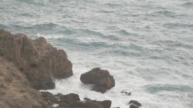 Ellerim titriyor, ama Büyük Dalgaların Deniz kıyısındaki uçurumun kenarından kayalara çarpmasını yakalıyorum..