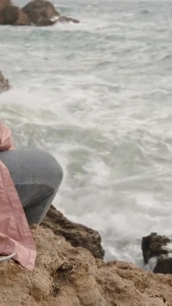 Vertikální Video Samostatná Žena Růžové Bundě Kapucí Sedí Skále Zírá — Stock video