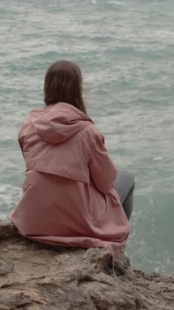 Κάθετο Βίντεο Μοναχική Γυναίκα Κάθεται Οδοντωτή Βράχους Και Περιληπτικά Παρακολουθεί — Αρχείο Βίντεο
