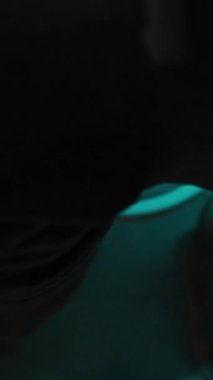 Dikey video. Gece, Loş Mavi Işık Altında, Tuvalette Bir Adam Oturur ve Telefonunda Bir Şey Bakmaya Başlar, Kaydırarak. Boşluğu Kopyalamak için Beyaz Ekranı kullan.