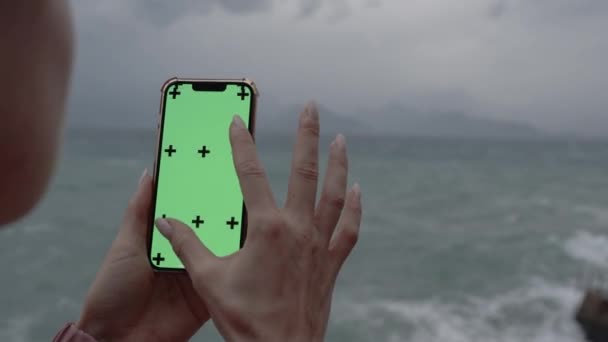 Okostelefon Zöld Képernyővel Nyomkövető Jelölőkkel Tenger Hegyek Hátterében Felhős Időben — Stock videók